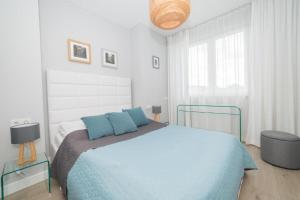 een witte slaapkamer met een blauw bed en een raam bij Apartament Pełen Wdzięku z balkonem in Polanica-Zdrój