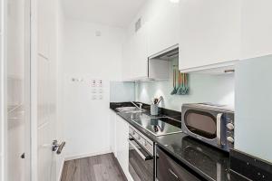 a white kitchen with a microwave and a counter at Cozy Covent Garden Gem in London