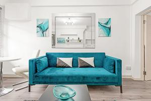 a blue couch in a living room with a mirror at Serene Escape in Covent Garden in London