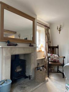 a living room with a fireplace and a mirror at Traditional Cotswold Stone Peaceful Cottage with stunning views in Stroud