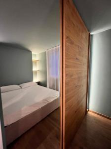 - une chambre avec un lit blanc et un mur en bois dans l'établissement LA DIMORA DEI MORI, à Catane