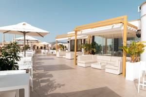 a patio at a hotel with white chairs and umbrellas at Hotel Casa Fuster G.L Monumento in Barcelona