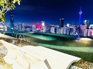 a white bench overlooking a city at night at AXON Suites Bukit Bintang By Sky Pool in Kuala Lumpur