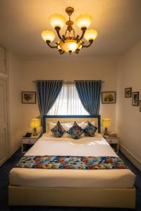 a bedroom with a bed with a chandelier and a window at Shinepukur Suites at Concord in Dhaka