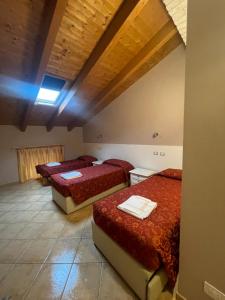 drie bedden in een kamer met houten plafonds bij Hotel La Cascina in Fontanellato