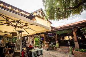 ein Restaurant mit Sonnenschirm, Tischen und Stühlen in der Unterkunft Pension Kokel in Dumbrăveni