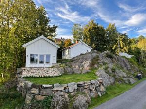 una casa en una colina con una pared de piedra en Cozy cottage close to idyllic archipelago with additional building if booked for more than 2 people, en Eydehamn