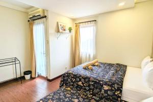 a bedroom with a bed with a floweredspread and two windows at Cottonwood Country Apartment at Majesty 715 in Bandung +7 photos