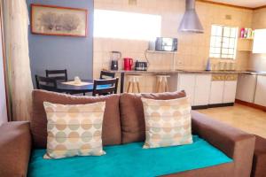 a living room with a couch and a kitchen at Yaxida's Warmth in Kasane