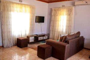 a living room with a couch and a tv at Yaxida's Warmth in Kasane