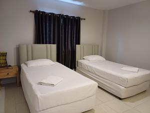 two beds in a room with black curtains at AT home hotel in Hua Hin