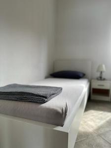 a white bedroom with a white bed with a gray blanket at Apartmani Krolo Trogir otok Čiovo in Trogir