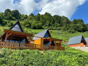 a log cabin with a deck and a house at Kalivi suit bungalov 1 in Ardeşen