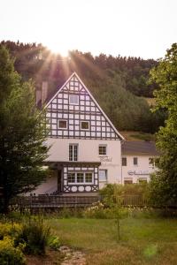 Hotel Tiefenhagen Sauerland في لينهشتات: بيت ابيض كبير مع اشعة الشمس عليه