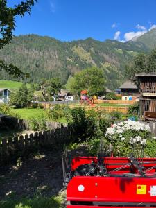 a red wagon in a yard with mountains in the background at Ferienwohnung mit wunderschöner Bergkulisse in Matrei in Osttirol