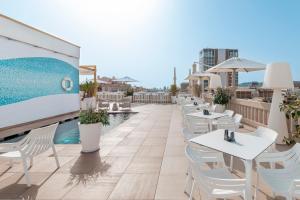 فندق كازا فوستر جي ال مونيمانتو  في برشلونة: صف من الطاولات والكراسي على فناء على السطح