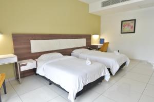 Cette chambre d'hôtel comprend 2 lits avec des draps blancs. dans l'établissement ILD UiTM Bandar Enstek Nilai, à Nilai