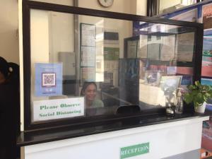 a woman is smiling behind a glass window at Marion's Inn Bldg 2 Bantayan powered by Cocotel in Bantayan Island