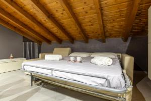 um quarto com uma cama com lençóis brancos e toalhas em Leonardo Academy in 5' - MXP, Laghi e Wi-Fi em Sesto Calende