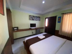 a bedroom with a bed and a desk with a computer at Dedy Beach Inn in Kuta