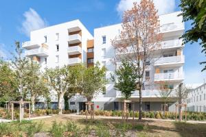 un immeuble d'appartements avec des arbres devant lui dans l'établissement OVELIA Lyon - Les Jardins d'Hortense, à Lyon