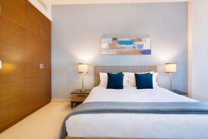 a bedroom with a large bed with blue pillows at Capital Living On Reem - The Arc Towers & The Gate in Abu Dhabi