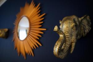 een spiegel en een olifantenkop naast een muur bij Enfield North London 3BR Apartment in Londen
