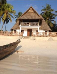 a building on a beach with a boat in the water at The Loft Zanzibar Kikadini Beach in Jambiani