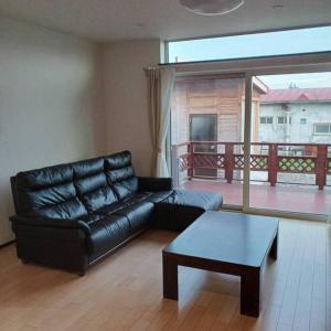 uma sala de estar com um sofá de couro preto e uma mesa de centro em アンドステイ上士幌 em Kami-shihoro