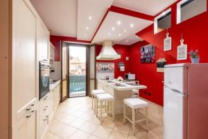 uma cozinha com paredes vermelhas e armários brancos em Leonardo Academy in 5' - MXP, Laghi e Wi-Fi em Sesto Calende