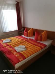 a large bed with red and orange blankets and pillows at Pension Am Stadion in Kölleda