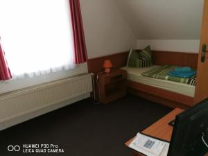 Cette petite chambre comprend deux lits et un bureau. dans l'établissement Pension Am Stadion, à Kölleda