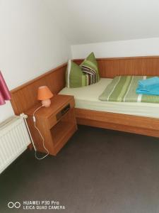 a small bedroom with a bed and a night stand at Pension Am Stadion in Kölleda