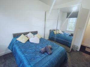 a bedroom with a blue bed and a mirror at Luxe & Stylish Centralised Watford Apt - Fast Wi-Fi & Free Parking Near Harry Potter Studios Tour in Watford