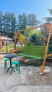 un banco del parque con una mesa y un columpio en Dato's GuestHouse, en Makhinjauri