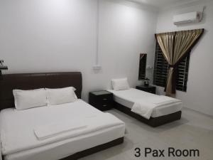 a bedroom with two beds and a window at Mersing Maple Villa in Mersing