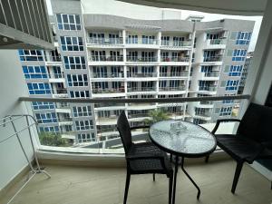 芭達雅中心的住宿－Large Deluxe Condo Grand Avenue Central Pattaya，阳台配有桌椅和大窗户。