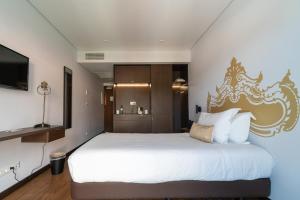 a bedroom with a large white bed with a gold headboard at Palacio Santa Catarina Hotel in Angra do Heroísmo