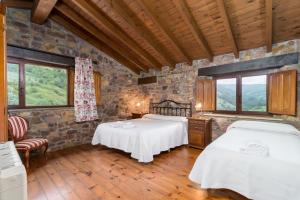 two beds in a room with a stone wall at Senda del pasiego in Liérganes