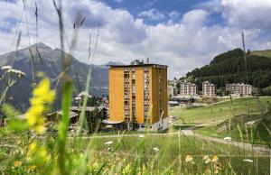 un edificio giallo in un campo con una montagna di Belambra Clubs Orcières 1850 - Le Roc Blanc a Orcières