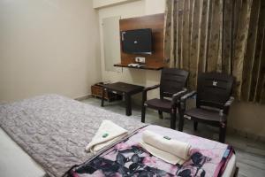 een slaapkamer met een bed en 2 stoelen en een bureau bij Rk Lodge in Amritsar +35 foto's