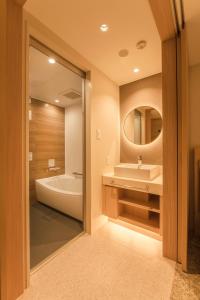 a bathroom with a tub and a sink and a mirror at Hotel Emion Sapporo in Sapporo