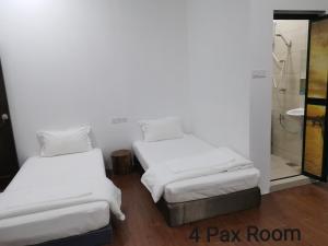two beds in a room with a shower at Mersing Maple Villa in Mersing