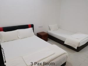 a room with two beds and a night stand at Mersing Maple Villa in Mersing