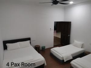 a bedroom with two beds and a room with a fan at Mersing Maple Villa in Mersing