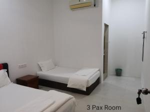 a room with two beds in a white room at Mersing Maple Villa in Mersing