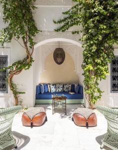 un divano blu in una stanza con alberi di Riad Idra a Marrakech