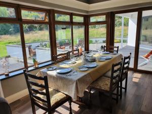 a dining room with a table and chairs and windows at Luxurious West Cork holiday home in Bantry