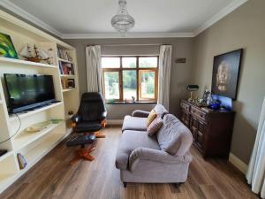 sala de estar con sofá, silla y TV en Luxurious West Cork holiday home, en Bantry