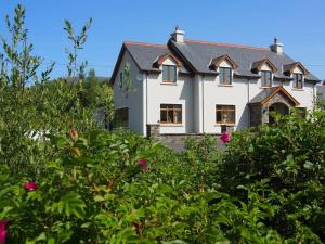 una casa blanca detrás de algunos árboles y flores en Luxurious West Cork holiday home, en Bantry